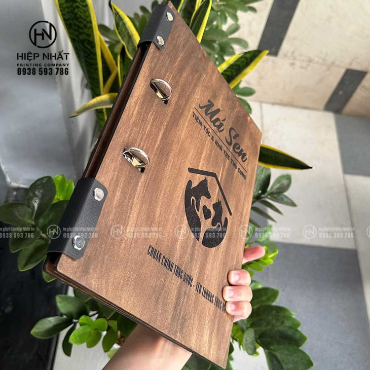 Góc nghiêng menu gỗ gáy còng – thể hiện còng inox và bìa khắc logo